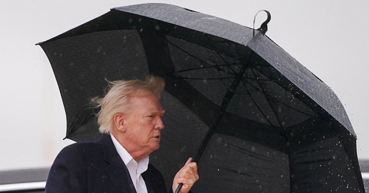Donald Trump attempts to board Air Force One while awkwardly handling an open umbrella at Joint Base Andrews.