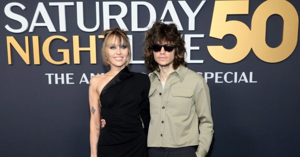 Miley Cyrus and Maxx Morando pose together on the red carpet at SNL50, February 2025