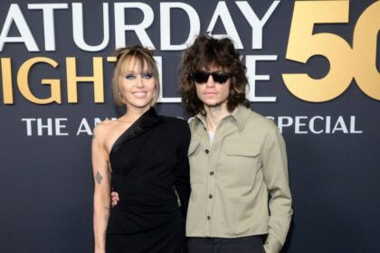Miley Cyrus and Maxx Morando pose together on the red carpet at SNL50, February 2025
