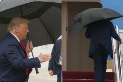 President Donald Trump struggles to close his umbrella while boarding Air Force One as an aide rushes to assist in the rain
