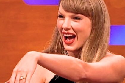 Taylor Swift showing her engagement ring while smiling on The Graham Norton Show