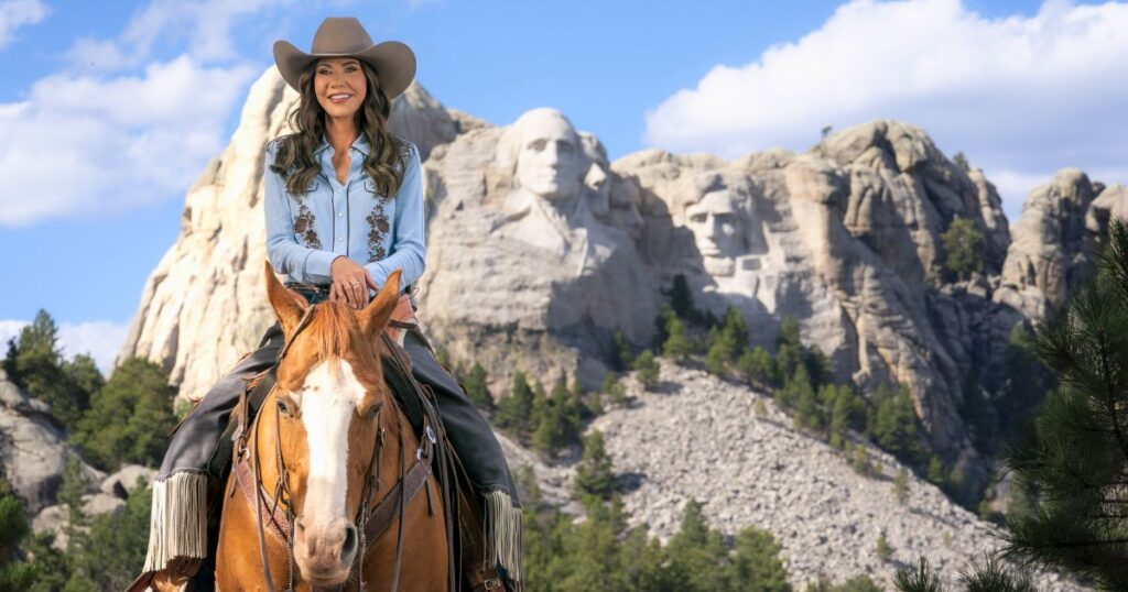Kristi Noem on horseback at Mount Rushmore filming a DHS immigration advertisement