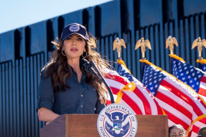 The photo was designed to be pure political theatre. Kristi Noem, hair sprayed into submission, blazer sharp enough to cut glass, sat behind a hefty stack of official papers. A staffer framed the shot just so, ready to capture the precise moment her pen hit the page. Moments later it was on X, the caption landing with all the subtlety of a campaign chant: “Build baby build.” This was meant to be the power image — the 54‑year‑old Homeland Security secretary personally green‑lighting new steel for Donald Trump’s border wall. Instead, it turned into a reminder of a far more awkward truth: the wall that was supposed to be paid for by Mexico is being financed, in black and white, by Americans. Kristi Noem, nicknamed “Ice Barbie” by her critics for her glossy, hyper‑managed image and love of viral stunts — including a notorious flamethrower clip — clearly thought the signing ceremony would signal momentum. DHS had frozen work on roughly 200 miles of planned barriers while it “reviewed” contracts. Her signature, the message went, would break the logjam. The wall was back on. The problem was the fine print. The contract she was so eager to showcase taps into the $46.5 billion that Congress tucked into the sprawling “One Big Beautiful Bill” (OBBB) for border infrastructure and enforcement. There is no foreign contribution. No clever funding wheeze from Mexico City. Just US taxpayers picking up the tab for more steel. That clashes head‑on with the story that helped launch Trump’s political career. On the 2015–16 campaign trail, he was unambiguous: “I would build a great wall… and I will have Mexico pay for that wall.” It was one of the core promises, chanted back at him at rallies, the verbal shorthand for a new, supposedly tougher kind of politics where America would no longer be the mug in every deal. So when Kristi Noem posted her polished “build baby build” moment, social media did what it does best and shredded the illusion in seconds. “I thought Mexico was paying for the wall?” one user wrote, the faux innocence doing more damage than any furious paragraph. Another went straight for the jugular: “Why would we purchase steel? Don said that Mexico was paying for it… what changed?” The “Ice Barbie” nickname resurfaced, not just as a personal dig but as a critique of the whole performance. “Performative… Mexico didn’t pay for the thing that Trump promised Mexico would pay for,” one commenter noted, encapsulating the sense that Noem’s pen was doing less governing than brand management. Strip away the snark, and there is a hard political fact underneath: by signing that contract, Kristi Noem effectively acknowledged that the central, crowd‑pleasing promise of the wall project has collapsed. The barrier is still being built. Mexico is not paying for it. Americans are. To be fair, Donald Trump and his team have been trying to rewrite this story for a while. By 2023, faced with awkward questions about funding, the former president had shifted into full revision mode. Critics, he said, were “losers” who didn’t understand that he had only pledged Mexico would pay for “a piece” of the wall. Then came the quiet admission: “Well, there was no legal instrument to do that.” That is a long way from the swaggering 2015 boast that “nobody builds walls better than me” and that Mexico would foot the bill. It’s also a glimpse of how the fantasy functioned: useful on stage, impossible on paper. While Trump worked the rally circuit, lawyers and appropriations committees in Washington quietly did the grown‑up job of finding domestic money. On Capitol Hill, the reality is straightforward. Congress — not President Andrés Manuel López Obrador — wrote border wall funding into OBBB. Hard‑right allies such as Arizona congressman Andy Biggs have bragged about helping to secure the cash and ensuring construction would be completed. For the MAGA base, the distinction between cheering the wall and paying for it may blur. For everyone else with a tax bill, it is much starker. That is why Kristi Noem’s little photo‑op stung. She wasn’t just signing off on a steel order; she was signing a line item that proves the United States is repeatedly absorbing the cost of a project repeatedly sold as free. The timing is not great for her personally either. Once touted as a breakout star in Trumpworld, Kristi Noem's stock has slipped. After two fatal ICE shootings in Minneapolis, she was reportedly stripped of responsibility for interior immigration enforcement. Oversight of that turf was handed to Donald Trump's favorite and self‑styled “border czar” Tom Homan — a man the president says he “knows and likes,' which in this ecosystem is more important than any organisational chart. Kristi Noem was told to focus solely on the southern border, a move that looked a lot like a demotion in all but name. Against that backdrop, the steel‑signing photo reads like an attempted comeback: look, I’m still central to the mission, still the one literally building the wall. The irony is brutal. In trying to prove her loyalty and relevance, she ended up highlighting the administration’s most glaring IOU. The “Ice Barbie” jibe may be petty, but the underlying charge is not: voters are being asked to forget the distance between the campaign fantasy — a magnificent barrier conjured on someone else’s dime — and the dull reality of multi‑billion‑dollar appropriations and domestic procurement. Forty‑six and a half billion dollars is not political pocket change. It is money that could be spent on roads, on schools, on hospitals. To wave it away with a glib “build baby build” while retro‑fitting the original pledge into something it never was is, frankly, an insult to anyone who has been paying attention. From the outside, it all feels grimly familiar. Grand slogans about borders and control have a habit of smashing into the brick wall of legal and fiscal reality. When they do, politicians often reach not for honesty but for better lighting and a sharper photo. Kristi Noem's pen stroke was supposed to project strength and progress. Instead, it captured the precise moment a campaign myth finally collided with the invoice. The steel will be bought, the fence posts will rise, and the bills will land — not in Mexico City, but in American mailboxes. The only real unknown now is whether the people who once chanted “Mexico will pay” care enough to notice that, in the end, it was always going to be them.