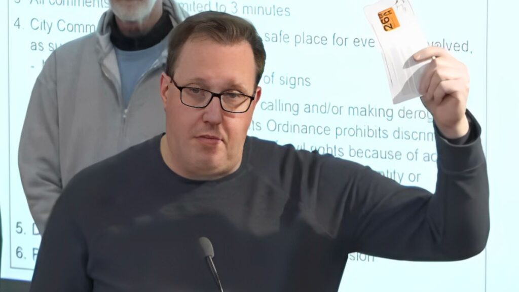 Lucas G.R. holds up expired license plate tabs at a Grand Rapids city commission meeting