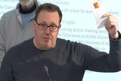 Lucas G.R. holds up expired license plate tabs at a Grand Rapids city commission meeting