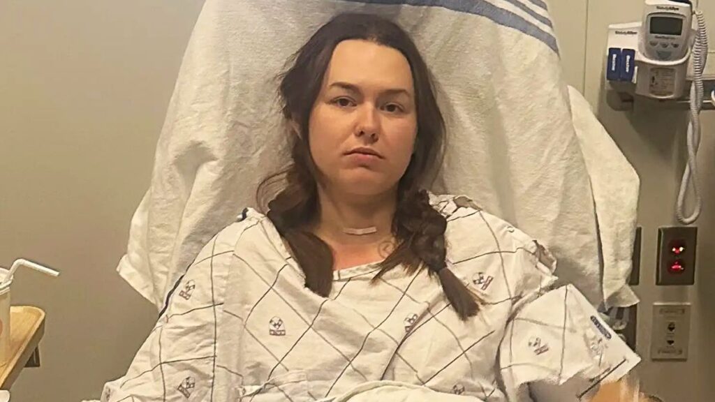 Young woman Claire Dougherty sitting in a hospital bed during cancer treatment