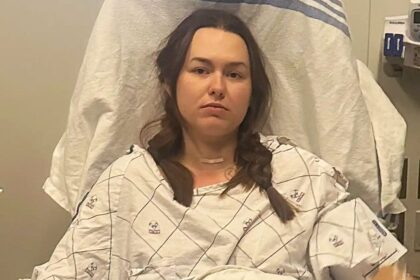 Young woman Claire Dougherty sitting in a hospital bed during cancer treatment